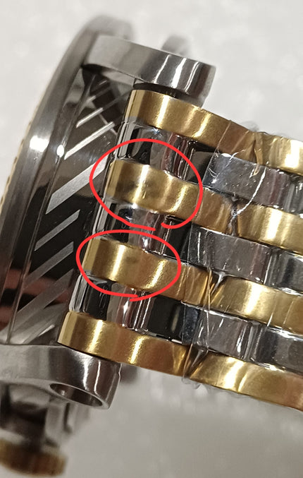 Close-up of two-tone bracelet links showing gold and silver stainless steel sections with defects circled
