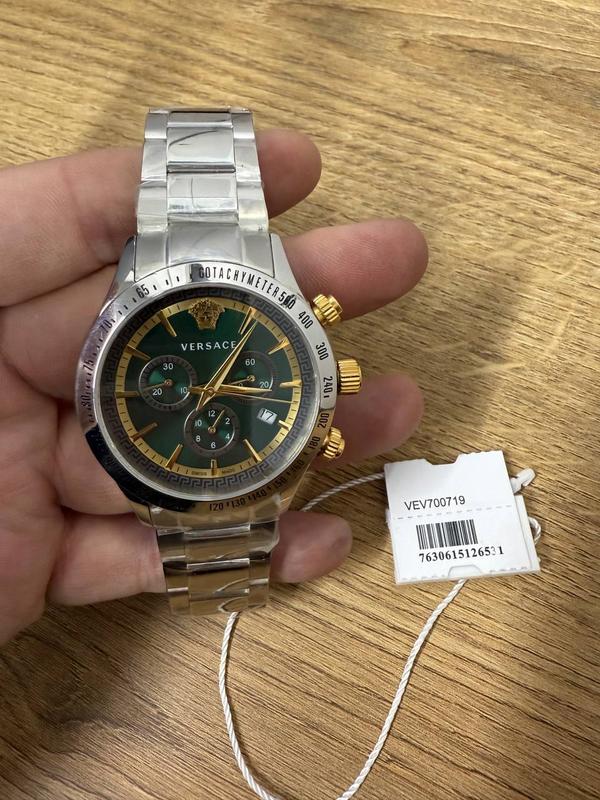 Versace VEV700719 watch on wrist showing teal dial with chronograph subdials and gold pushers