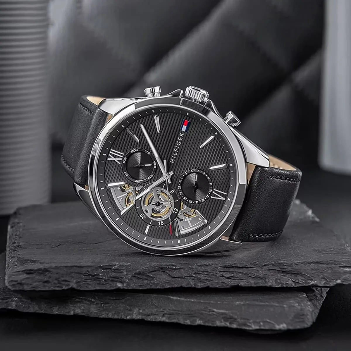 Angled studio view of Damon chronograph watch highlighting skeleton dial and black leather strap