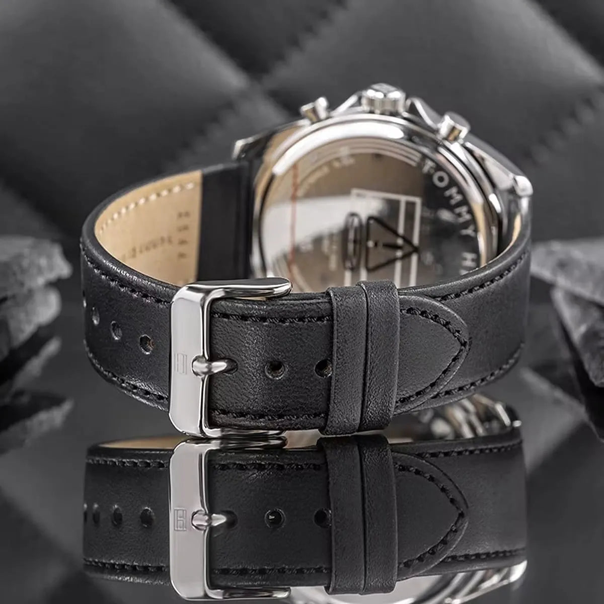 Close-up of Damon watch strap showing black leather band with tan lining, steel buckle, and adjustment holes