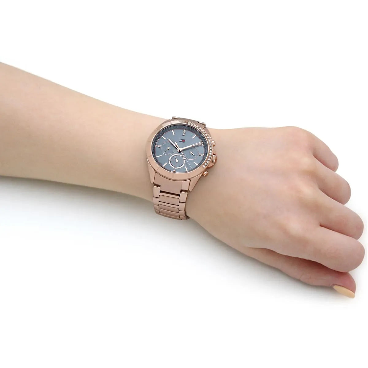 Tommy Hilfiger Kennedy multifunction watch on woman's wrist showing rose gold case and blue dial