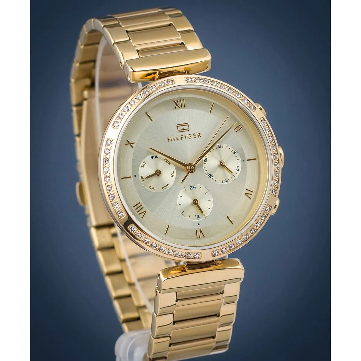 Tommy Hilfiger 1782392 women's gold chronograph watch against blue background