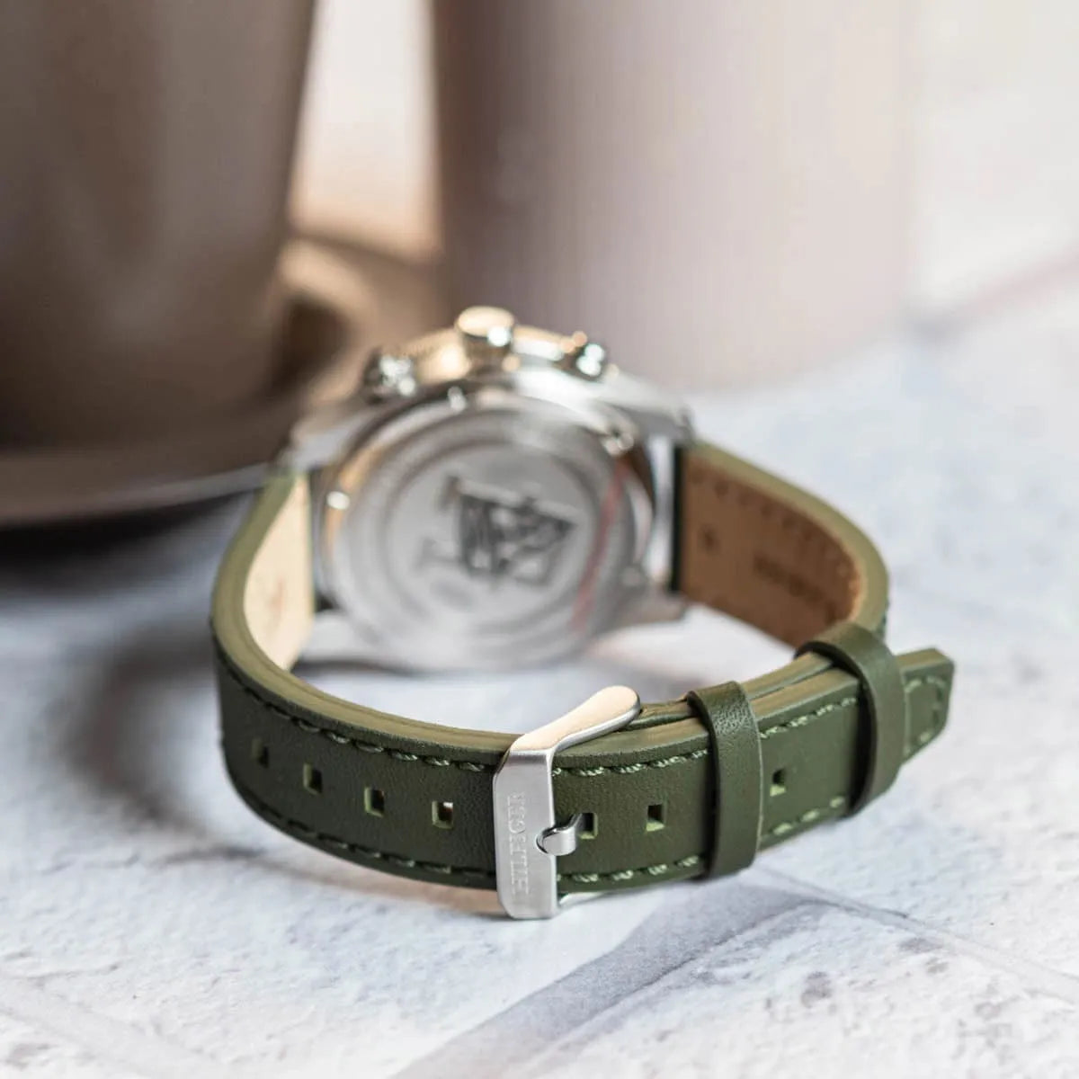 Caseback of Tommy Hilfiger chronograph watch showing Tommy Hilfiger logo on green leather strap