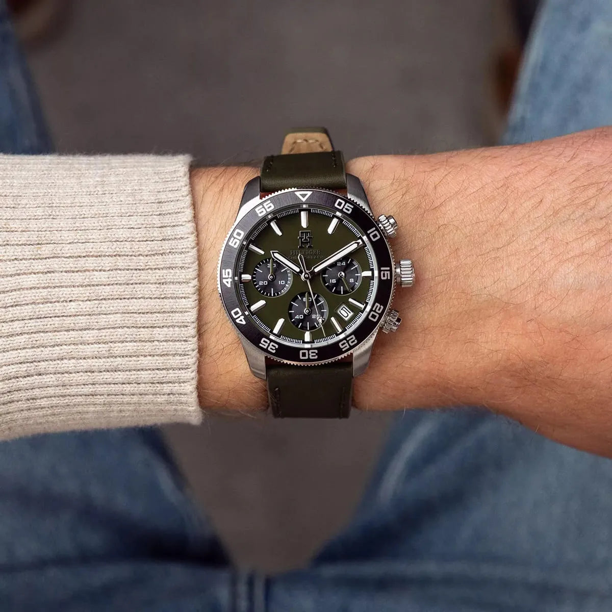 Tommy Hilfiger green chronograph watch worn on wrist with light-colored long-sleeve shirt