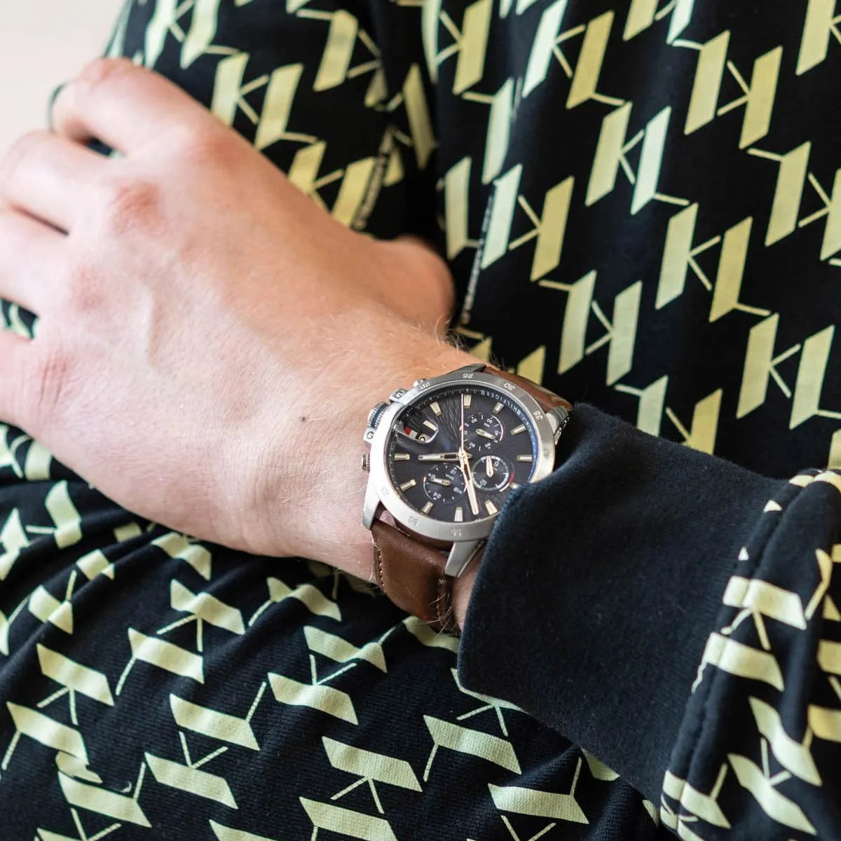 Tommy Hilfiger Jameson watch worn on wrist with brown leather strap over patterned yellow and black sleeve