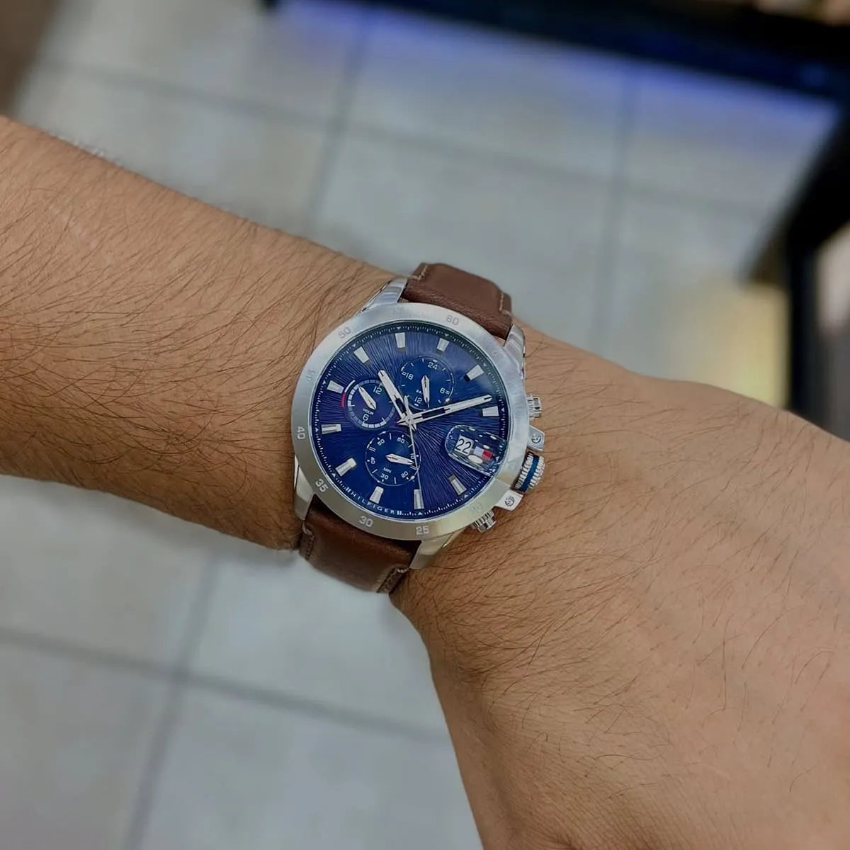 Tommy Hilfiger Jameson chronograph watch on wrist showing blue dial, chronograph subdials, and brown leather strap