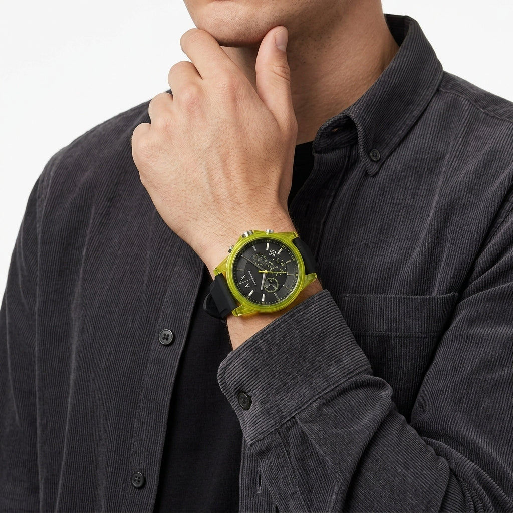 A close-up of a man wearing a Swatch wristwatch with a bright lime green case, black dial, and black strap, paired with a dark gray corduroy shirt.