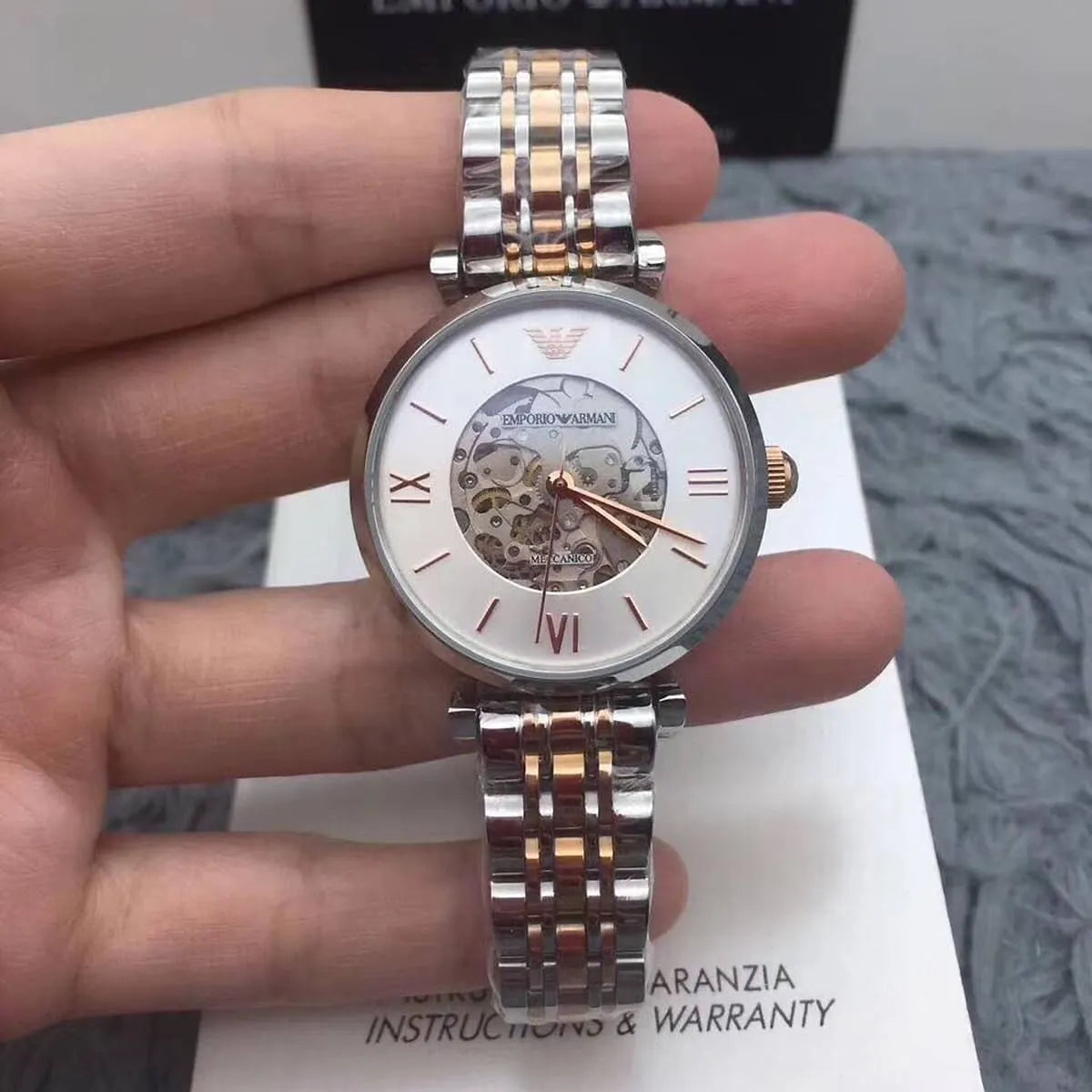 Emporio Armani Gianni T-Bar watch worn on wrist with box showing silver skeleton dial and two-tone metal bracelet