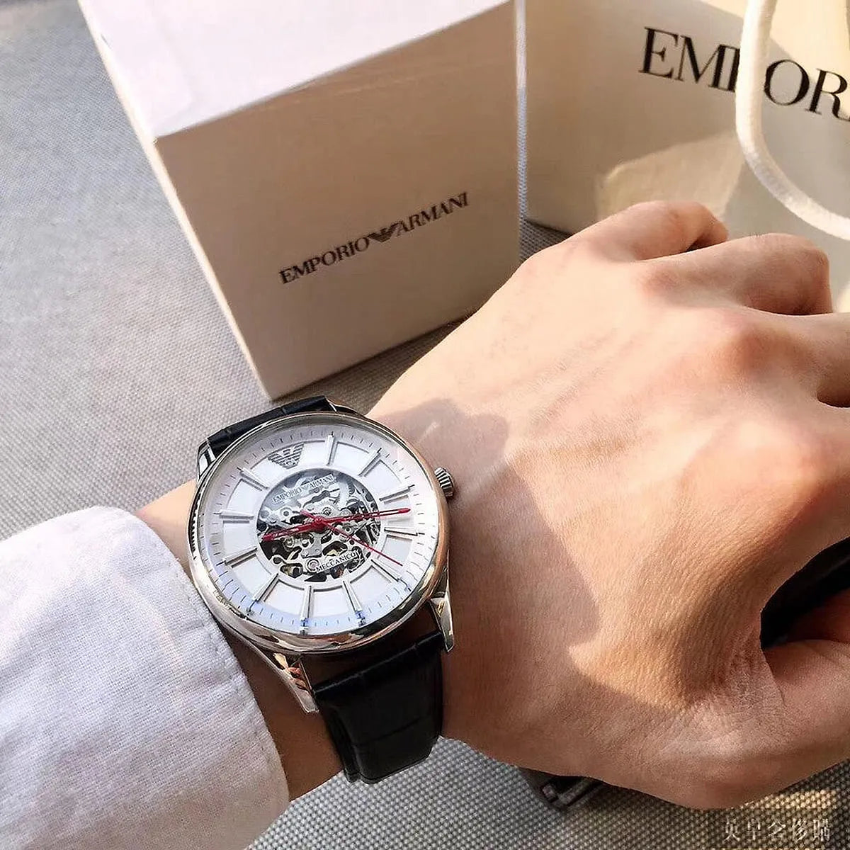 AR2072 Emporio Armani Meccanico watch on wrist next to packaging box