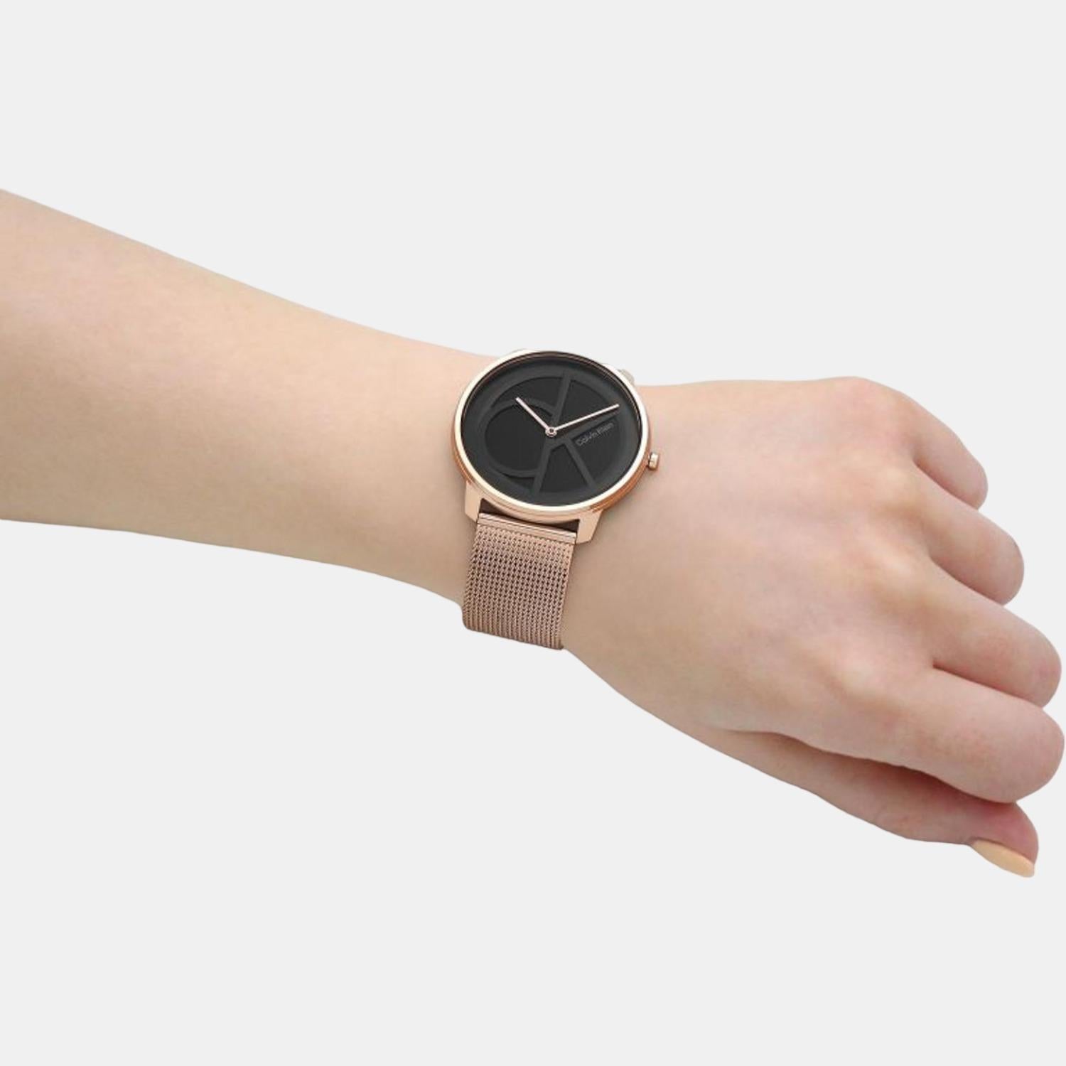 Calvin Klein black dial watch with gold mesh strap worn on wrist
