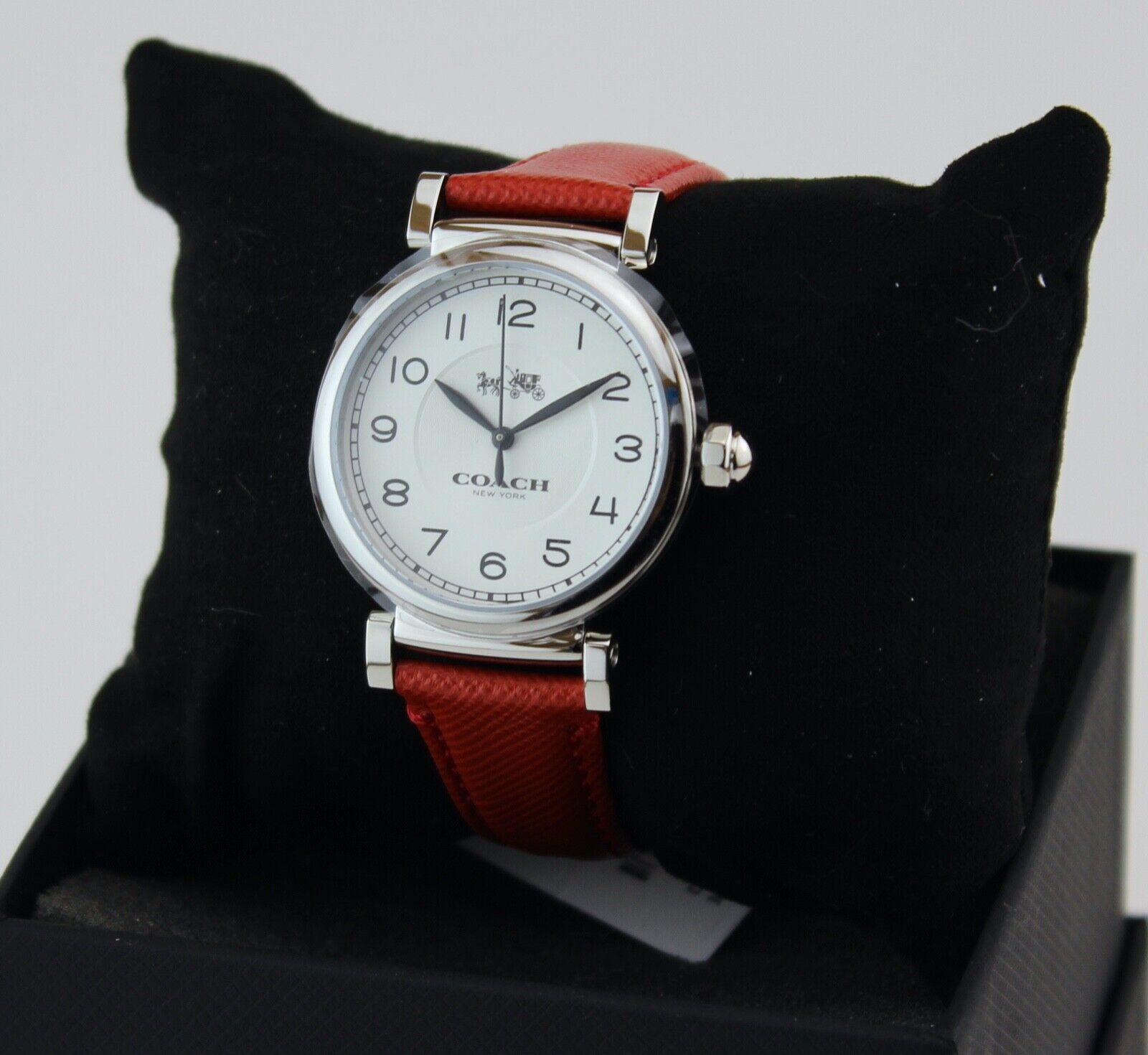 Coach Madison watch displayed on black stand showing red leather strap and silver case