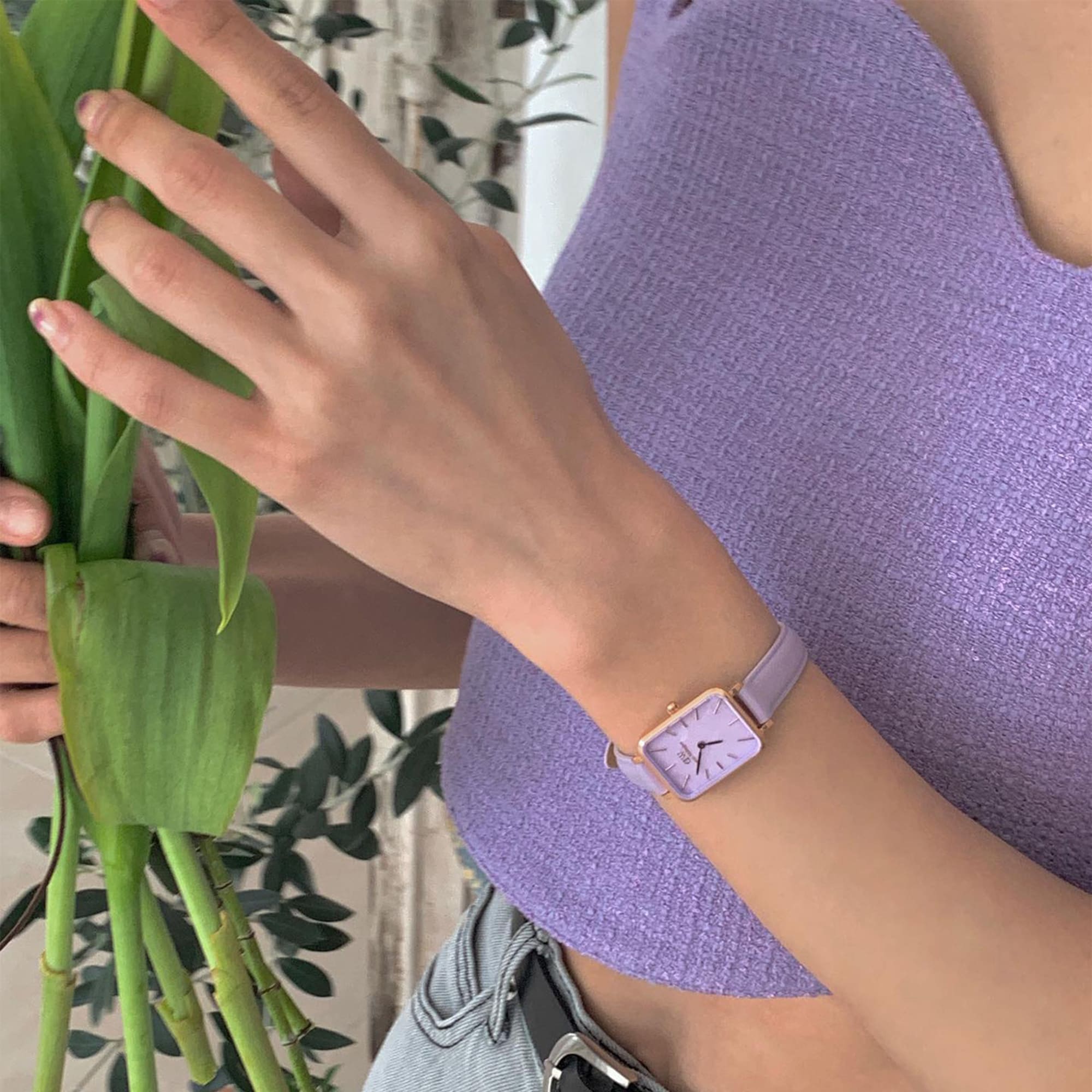 Women's wrist wearing Daniel Wellington rose gold watch with lavender leather strap