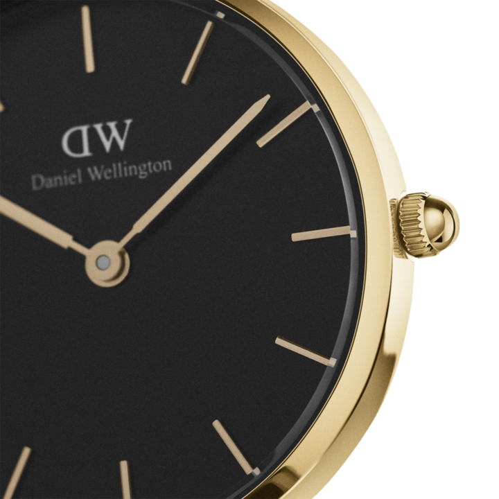 Close-up of black dial with gold hour markers and Daniel Wellington branding