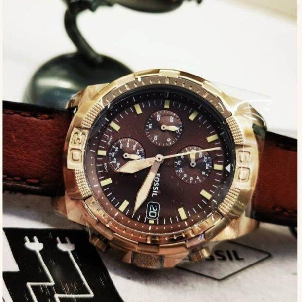 Fossil Bronson watch displayed with accessories on dark surface