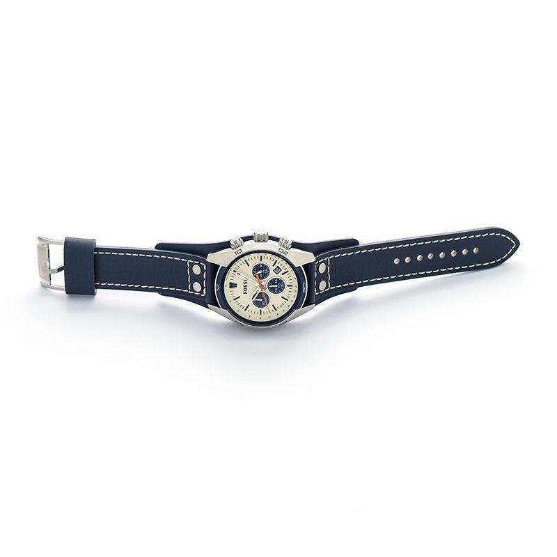 Fossil Coachman watch displayed on wrist with navy leather strap and contrast white stitching