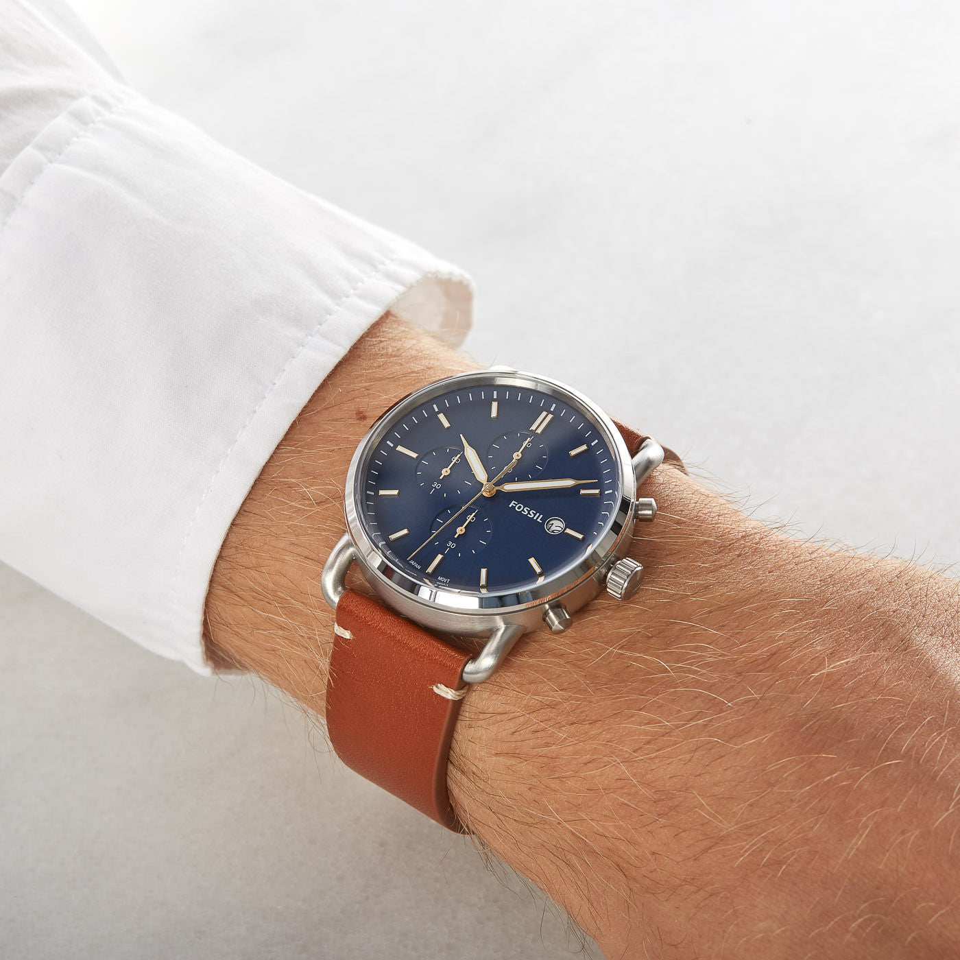 Fossil Commuter chronograph watch worn on wrist with blue dial and cognac brown leather strap
