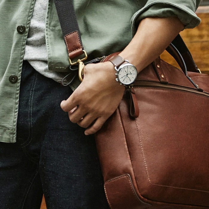 Fossil Commuter watch on wrist with cream dial paired with brown leather bag