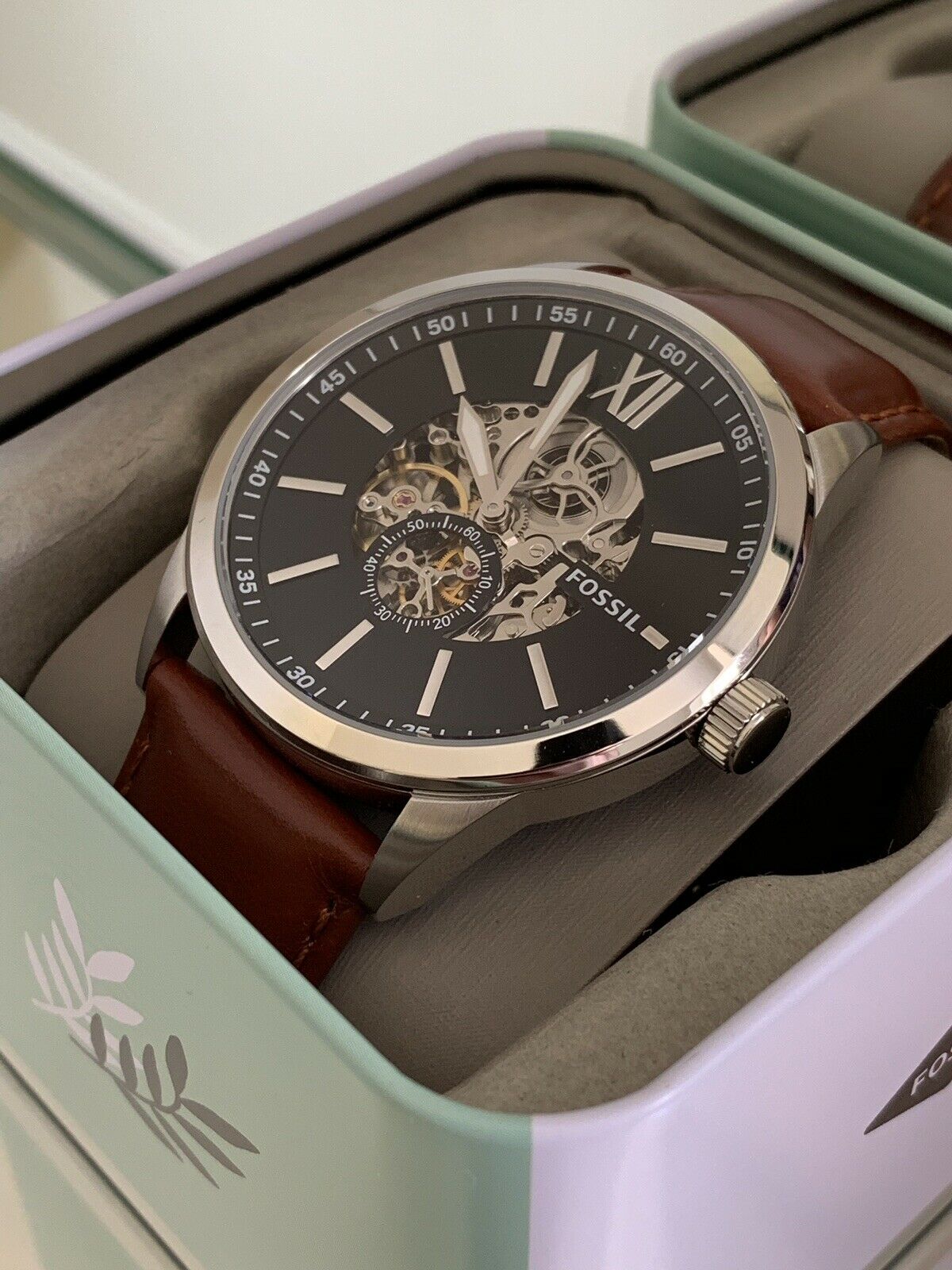 Fossil Flynn watch displayed in branded retail box showing skeleton dial and brown leather strap