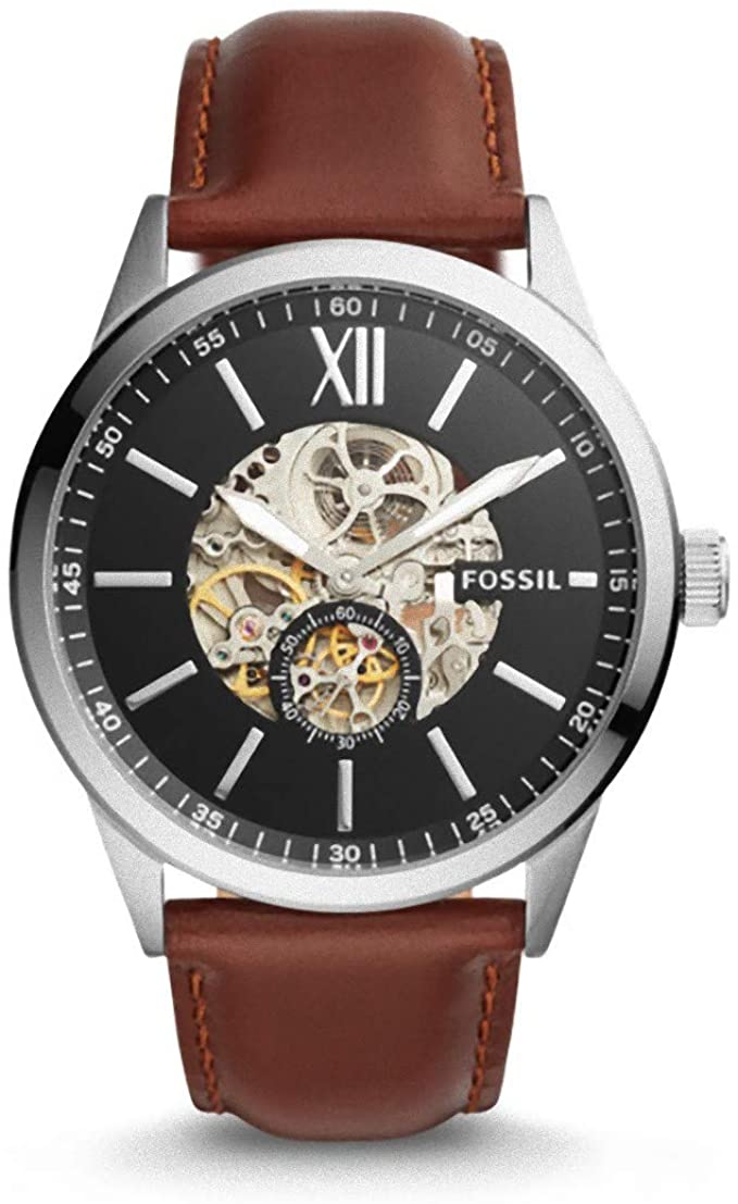 Fossil Flynn automatic men's watch with skeleton dial showing gold-tone gears and Roman numerals on black background