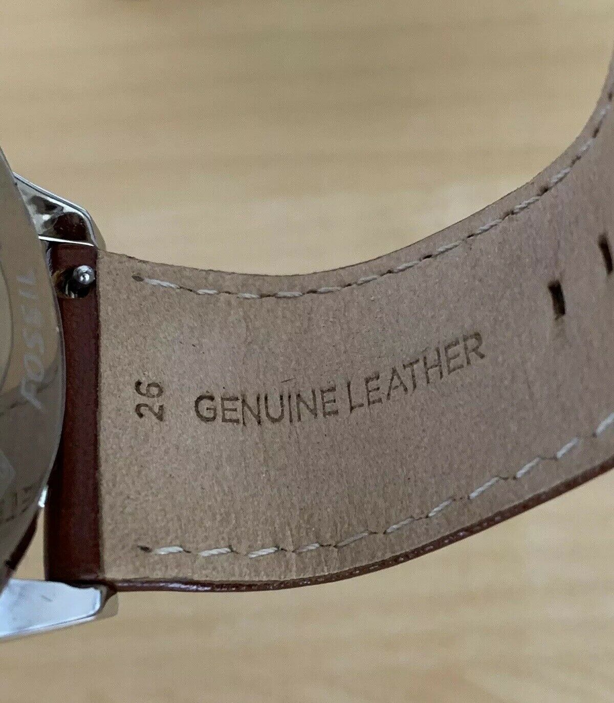 Close-up of Fossil Flynn brown genuine leather strap showing stitching and brand marking