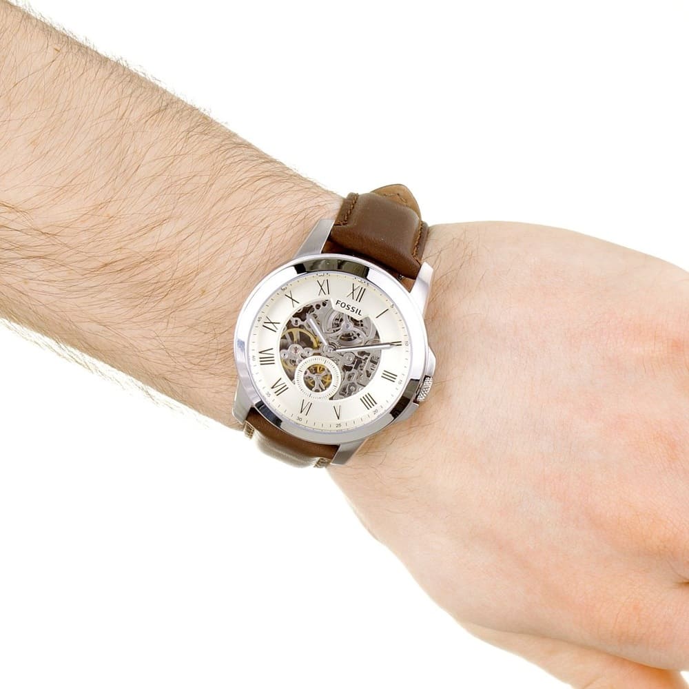 Fossil Grant watch worn on wrist displaying white skeleton dial with chronograph sub-dials and brown leather strap