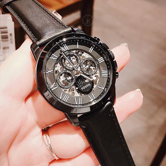 Fossil Grant automatic watch worn on wrist showing black skeleton dial and leather strap