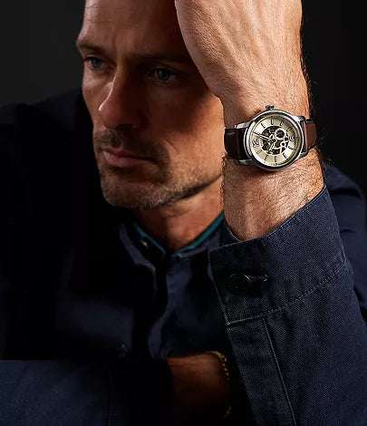 Fossil Heritage Automatic watch worn on man's wrist with cream skeleton dial visible