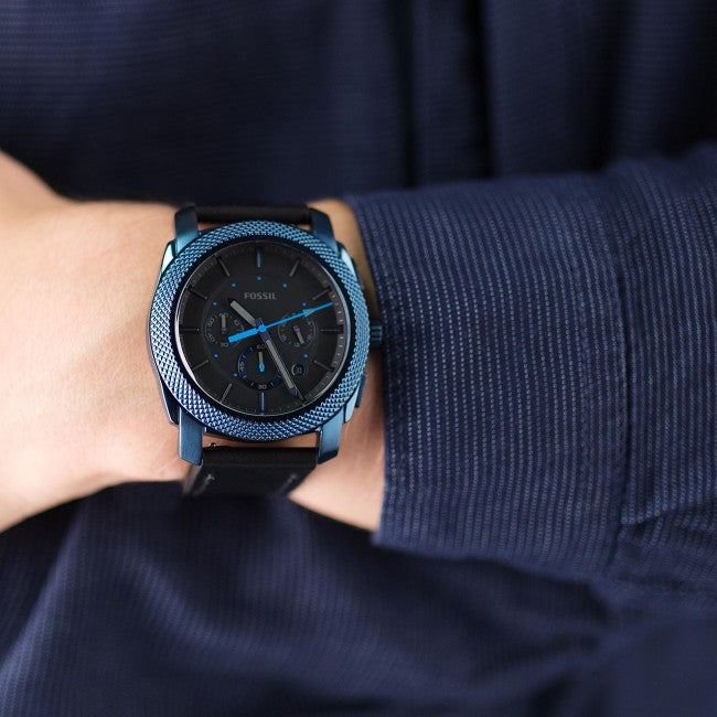 Fossil Machine chronograph worn on wrist against navy blue fabric