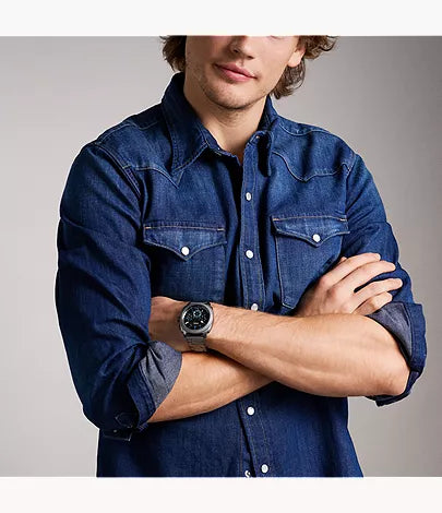 Fossil Machine chronograph watch worn on wrist against denim shirt