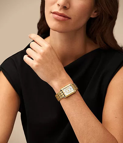 Woman wearing Fossil Raquel ES5304 gold-tone watch on wrist with black sleeve