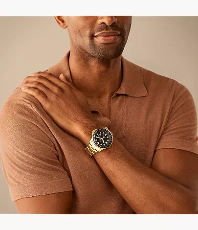 Fossil Blue GMT watch worn on wrist with gold-tone stainless steel bracelet