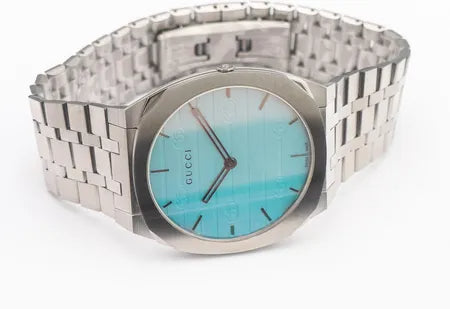 Gucci 25H watch on wrist displaying turquoise dial with Gucci branding