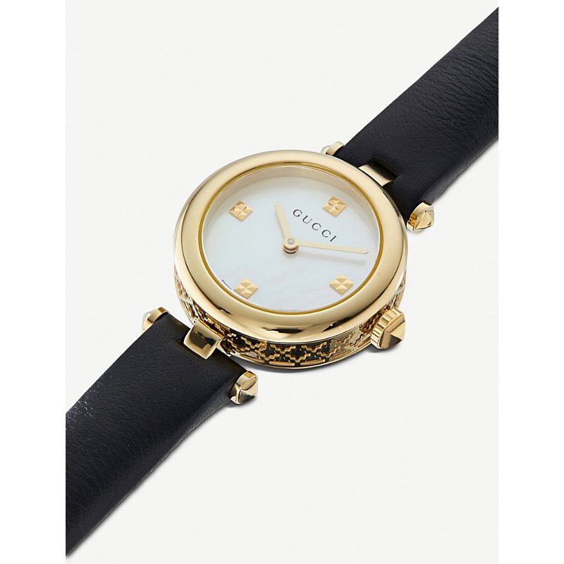 Gucci Diamantissima watch on wrist showing mother of pearl dial face and gold accents