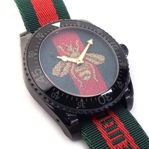 Detail of Gucci Dive YA136216 dial showing embroidered gold bee on green and red background