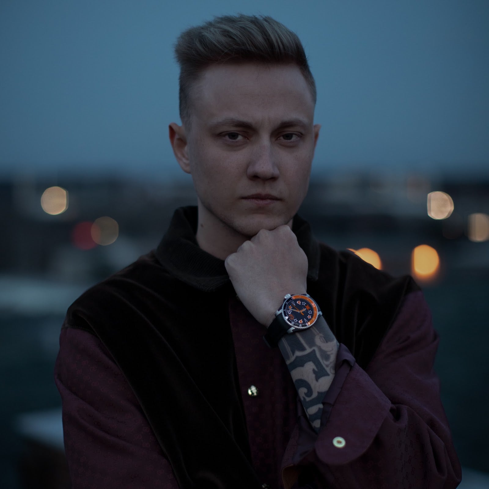 Gucci Dive watch on wrist with orange bezel and star motif dial against evening sky backdrop