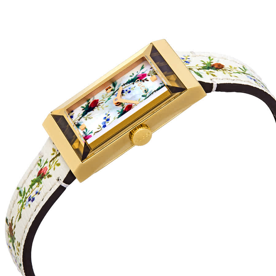 Gucci G-Frame watch at angle showing gold case, floral mother of pearl dial, and white leather band
