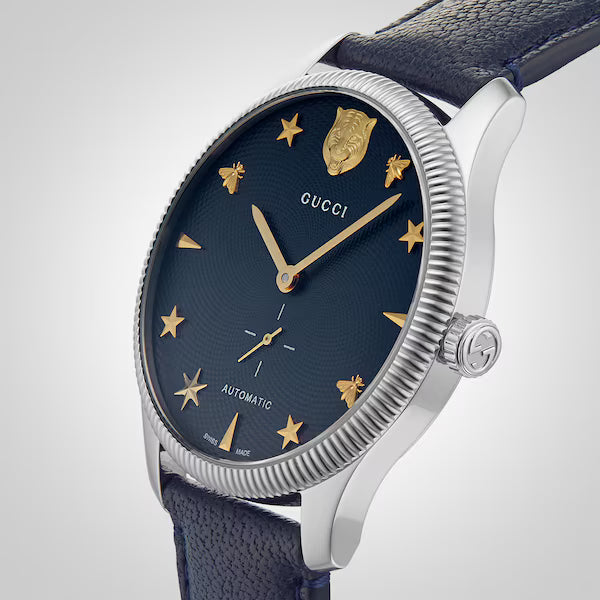 GUCCI G-Timeless watch at angle showing blue dial with gold star markers and leather strap