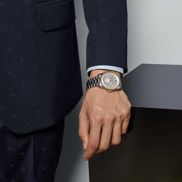 Gucci G-Timeless watch worn on wrist with silver dial and two-tone steel bracelet