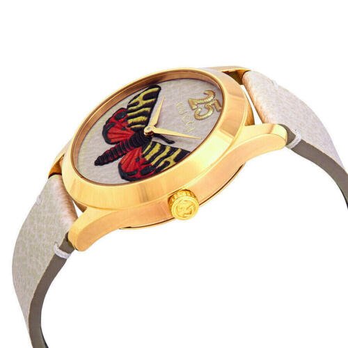 Gucci G-Timeless butterfly watch angled view showing gold case and cream leather strap