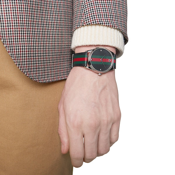 Gucci G-Timeless watch worn on wrist showing dial and striped strap