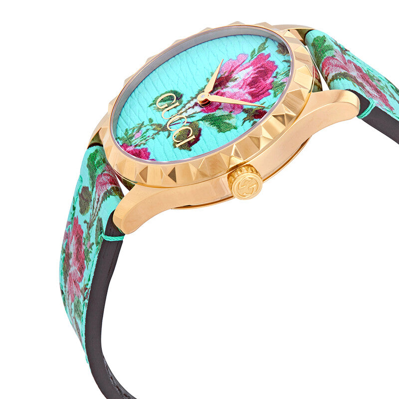 Side angle view of Gucci G-Timeless watch with gold-tone case and floral leather strap