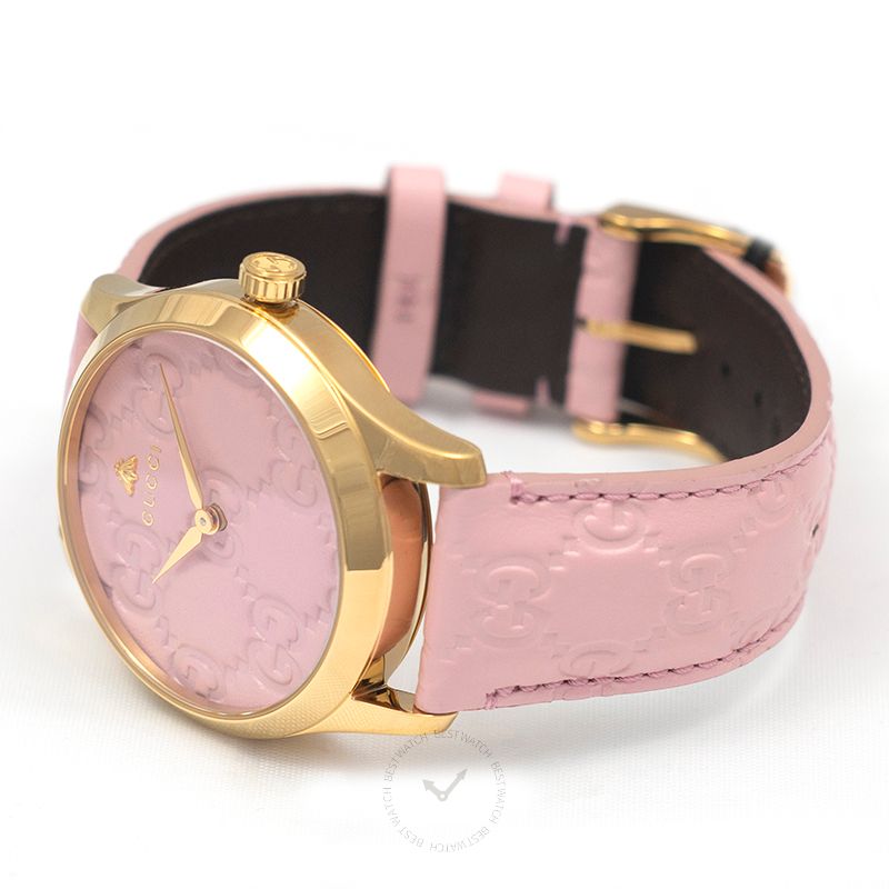 Gucci G-Timeless watch at angle showing gold case, pink dial, and pink leather strap with black interior