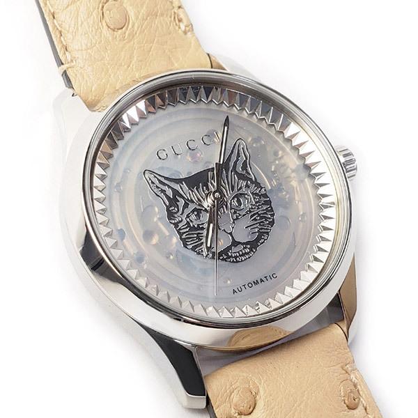 Close-up of transparent mother of pearl dial with twin panther design and automatic movement text on Gucci G-Timeless