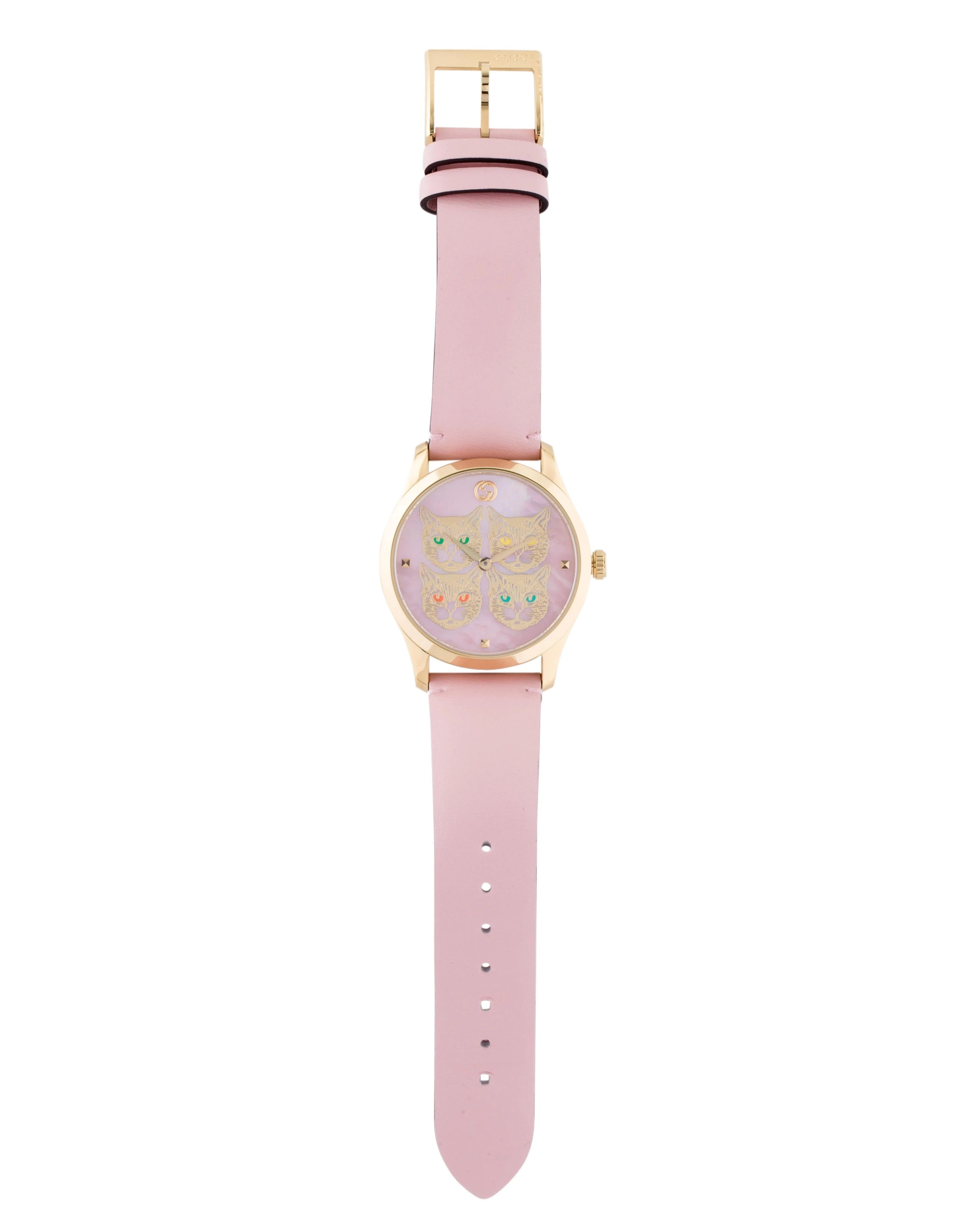 Pink leather strap of Gucci G-Timeless watch with gold-tone buckle and case visible at top