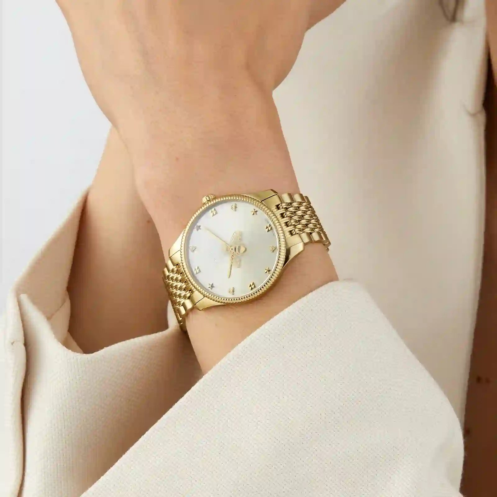 Gucci G-Timeless slim watch worn on wrist, showing silver dial and gold mesh bracelet