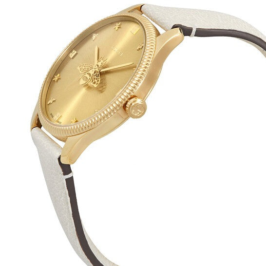 Gucci G-Timeless watch at angle showing golden case, dial, and cream leather strap