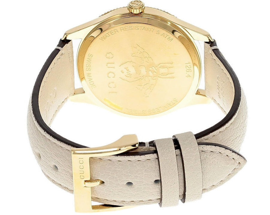 Gucci G-Timeless women's watch on wrist showing cream leather strap and golden case