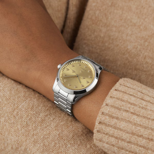 Gucci G-Timeless watch worn on wrist with champagne dial