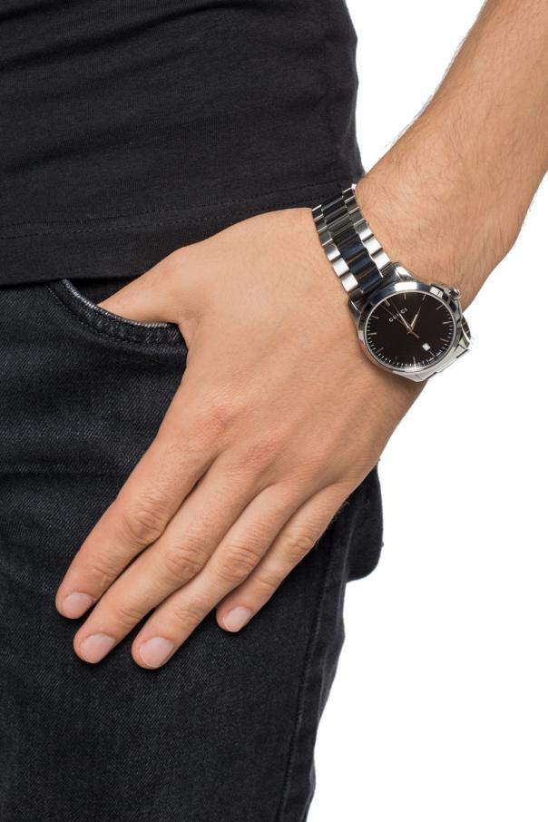 Gucci G-Timeless watch worn on wrist showing black dial and steel bracelet