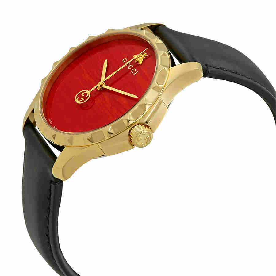 Gucci G-Timeless watch angle view showing red dial, gold case, and black leather strap